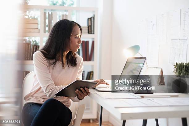 mixed race businesswoman using laptop - african american woman with tablet stockfoto's en -beelden