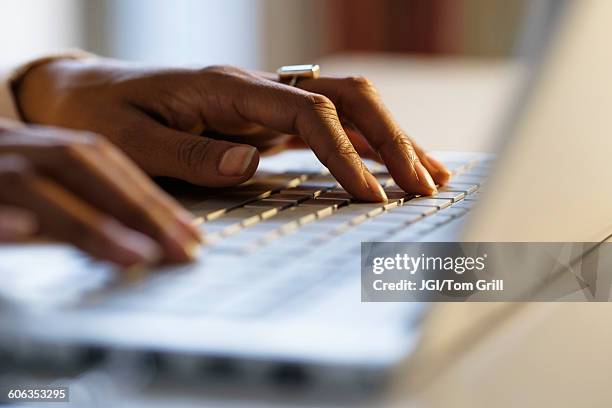 mixed race woman using laptop at desk - computer hacking stock-fotos und bilder