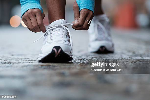 mixed race runner tying shoelaces - zapatos mujer fotografías e imágenes de stock