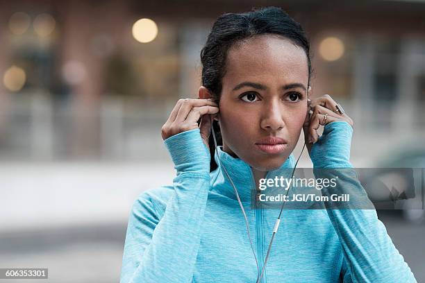 mixed race runner listening to earbuds - in ear headphones photos et images de collection