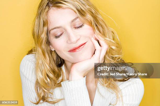 smiling woman resting chin in hand - effortless stock-fotos und bilder