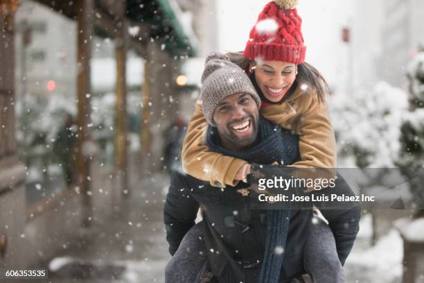 man carrying girlfriend piggyback in snow - i love new york foto e immagini stock