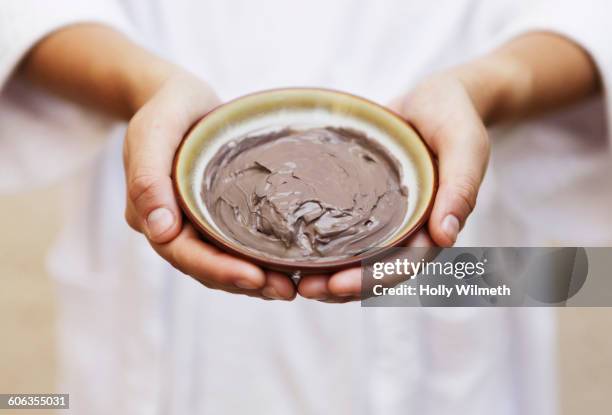 hands holding bowl of mud skin treatment - trattamento di benessere foto e immagini stock