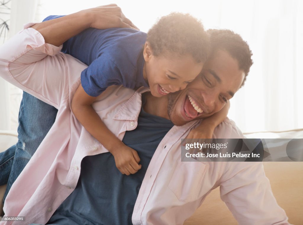 Mixed race father and son playing on sofa