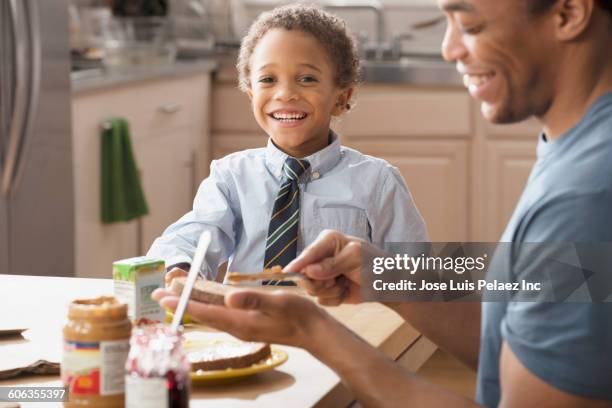 mixed race father making lunch for son in kitchen - make room make room stock pictures, royalty-free photos & images