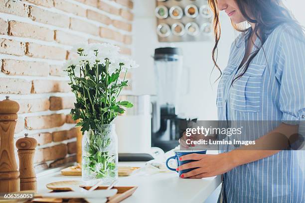 caucasian woman stirring coffee in kitchen - stirring stock pictures, royalty-free photos & images