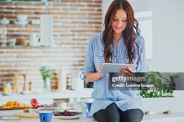 caucasian woman using digital tablet in kitchen - procedimiento fotografías e imágenes de stock