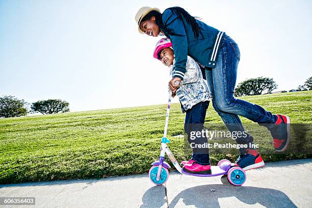 black mother and daughter riding scooter - ropa protectora deportiva fotografías e imágenes de stock