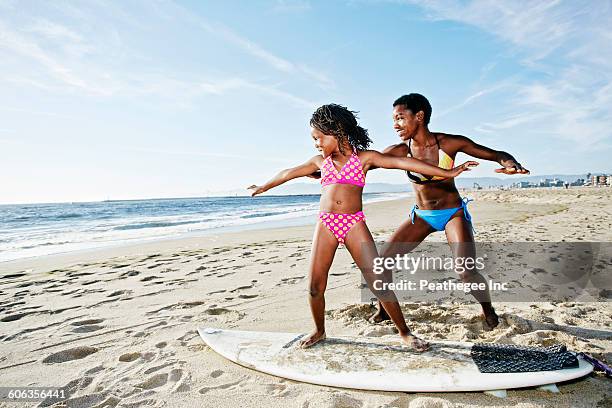 black mother teaching daughter to surf on beach - beach la stock pictures, royalty-free photos & images