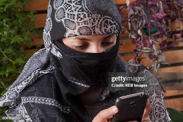 hispanic woman in headscarf using cell phone - burka stock pictures, royalty-free photos & images