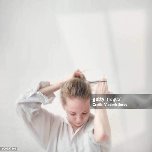caucasian teenage girl tying her hair into bun - girl hair stock pictures, royalty-free photos & images