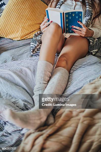 woman reading book on bed - knee length stock pictures, royalty-free photos & images