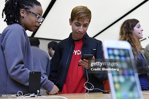 An employee, left, assists a customer with an iPhone 7 Plus smartphone at an Apple Inc. In San Francisco, California, U.S., on Friday, Sept. 16,...