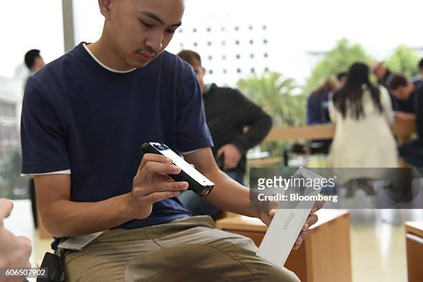 An employee scans an iPhone 7 smartphone for a customer at an Apple Inc. In San Francisco, California, U.S., on Friday, Sept. 16, 2016. Shoppers...