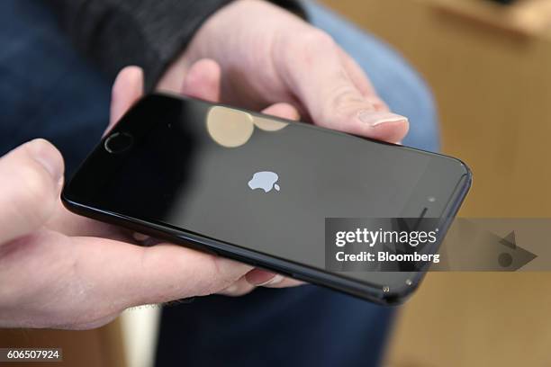 Customer holds a newly purchased iPhone 7 smartphone at an Apple Inc. In San Francisco, California, U.S., on Friday, Sept. 16, 2016. Shoppers looking...