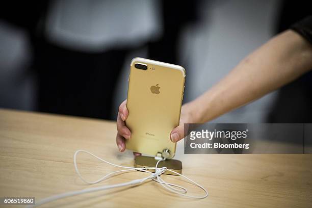 An employee picks up an iPhone 7 Plus smartphone at an Apple Inc. Store in New York, U.S., on Friday, Sept. 16, 2016. Shoppers looking to buy Apple...