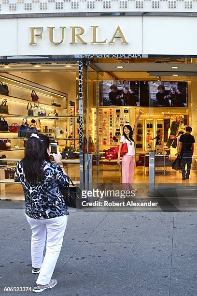 August 27, 2016: A visitor to New York City strikes a pose at the entrance to the Furla store on Fifth Avenue on August 27, 2016. The Italian womens'...