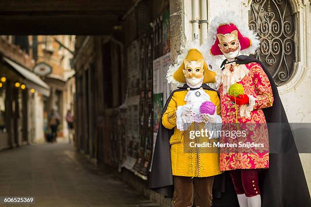 couple in cat costumes with wool balls at alleyway - venetiaans masker vasthouden stockfoto's en -beelden