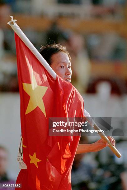 Chinese long-distance runner Wang Junxia holding her flag after winning the Women's 10,000 Metres race at the 4th International Association of...