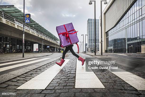 young girl running with large gift on street - surprise gift stockfoto's en -beelden