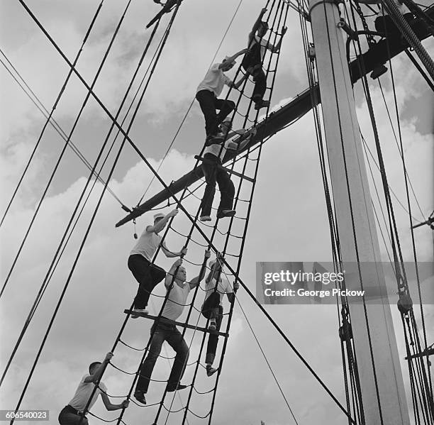 Young men swarm up the rigging of the sailing ship 'Joseph Conrad', moored at Mystic, Connecticut, USA, circa 1955. They are taking part in a project...