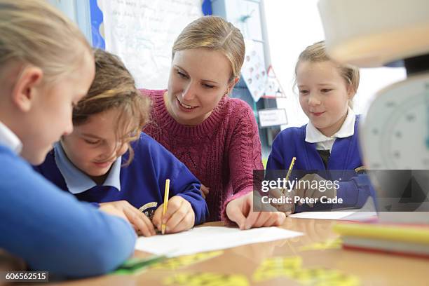teacher helping students in class - maestra foto e immagini stock