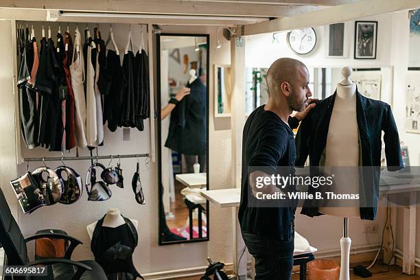 fashion designer standing in his workshop - clothes rack stock-fotos und bilder