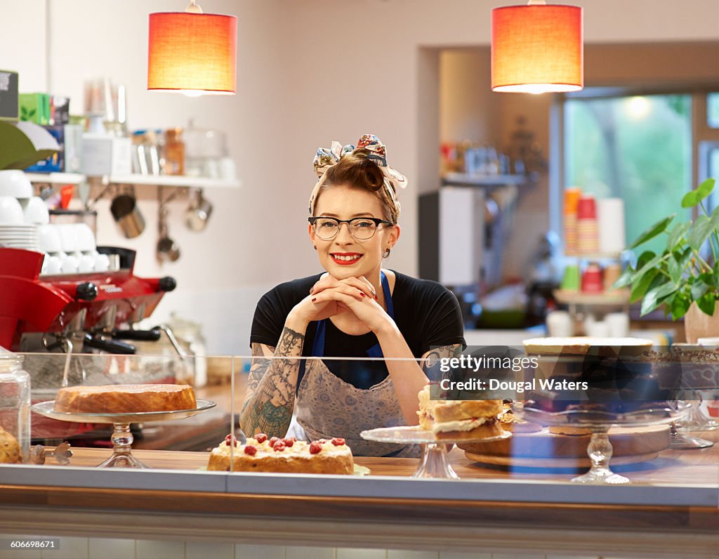 Woman behind counter in cake shop.