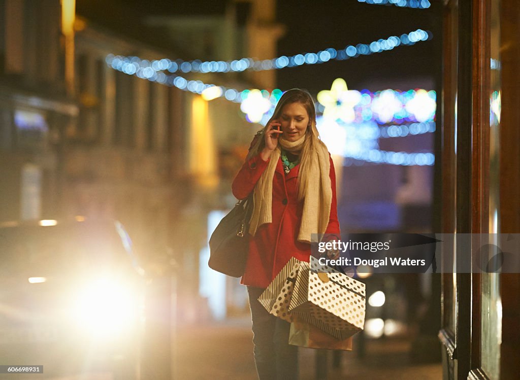 Woman walking with shopping and using phone.
