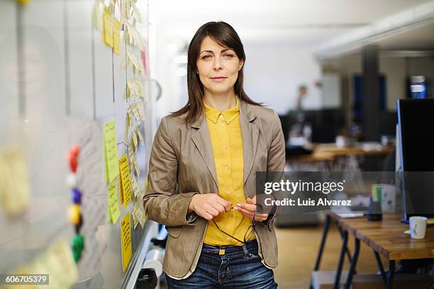 confident businesswoman standing by board - woman whiteboard stock-fotos und bilder