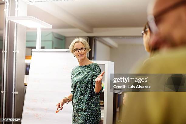 businesswoman giving to colleagues - flipchart stock-fotos und bilder