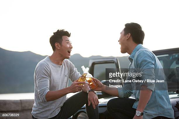 happy friends drinking beer beside a jeep - beer bottle mouth stock-fotos und bilder
