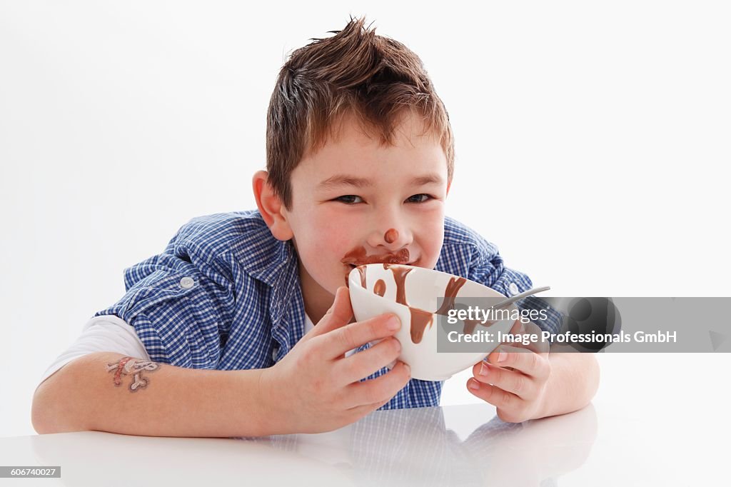 Small boy eating chocolate pudding