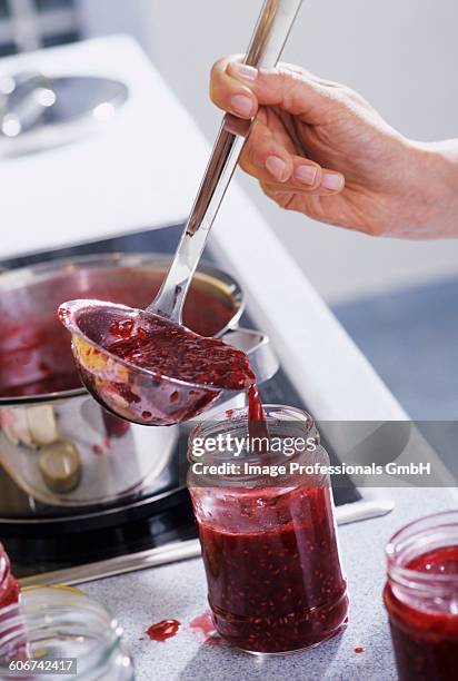 raspberry jam being ladled into a screw-top jar - raspberry jam stock pictures, royalty-free photos & images