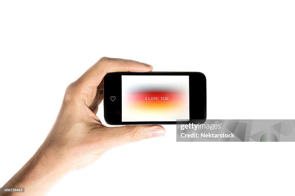 Cropped Hand Showing I Love You Text In Smart Phone Against White Background