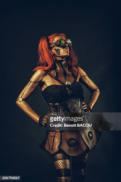 steampunk robot woman with red hair standing with hands on hips - gold metal rock stock-fotos und bilder