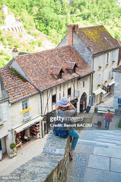 young woman sitting on a wall taking a picture, rocamadour, lot, france - rocamadour ストックフォトと画像