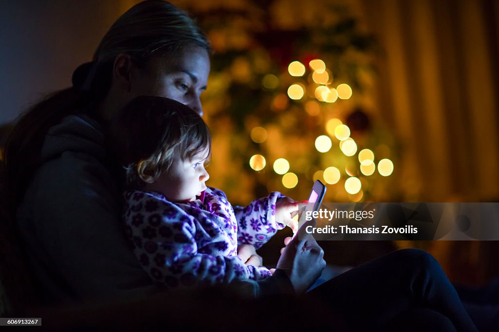 Mother with her son using a smartphone in the dark