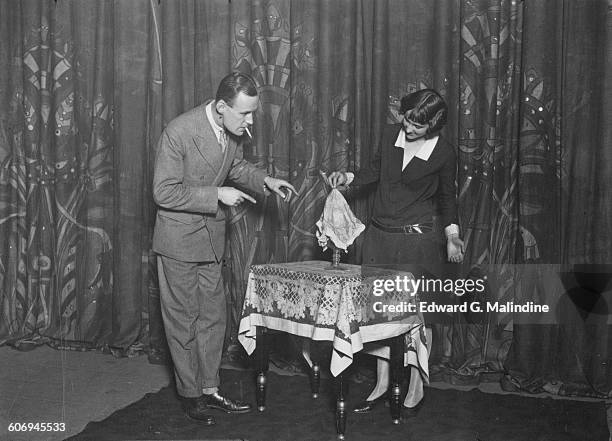 British stage magician Noel Maskelyne watches his sister Mary perform the disappearing water trick, UK, 7th October 1927. Their father was famous...