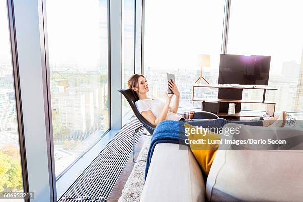 woman in apartment using digital tablet - dario secen stock-fotos und bilder
