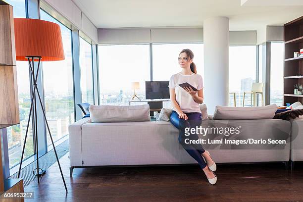 woman in apartment using digital tablet - dario secen stock-fotos und bilder
