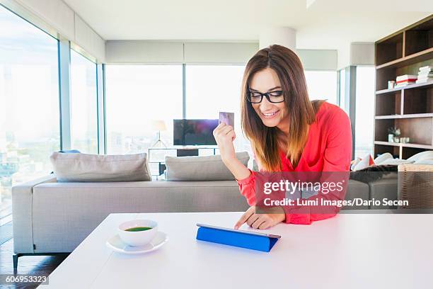 woman in apartment shopping online with digital tablet - dario secen stock-fotos und bilder