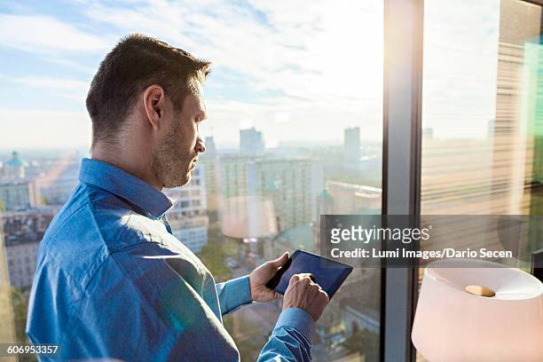 businessman in apartment using digital tablet - dario secen stock-fotos und bilder