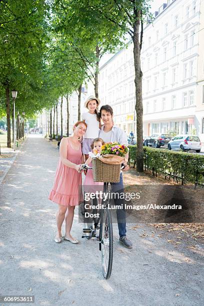 family with two children pushing bicycle in city - alexandra dost stockfoto's en -beelden