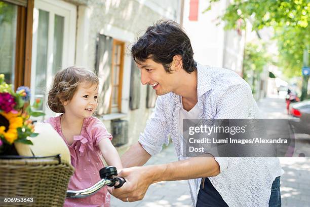 father and daughter pushing bike together - alexandra dost stockfoto's en -beelden