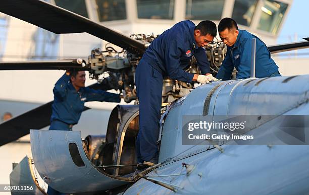 Staff check on helicopter before lifting off the Amphibious transport dock "Kunlun Shan" during China-Russia Naval Drill "Joint Sea-2016" on...