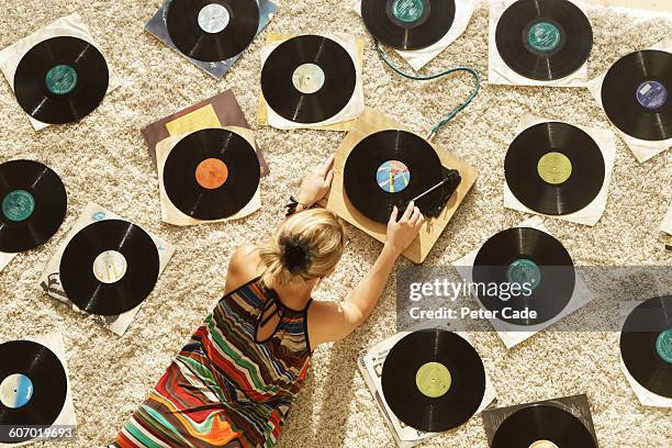 woman on floor playing records - multi colored dress photos et images de collection