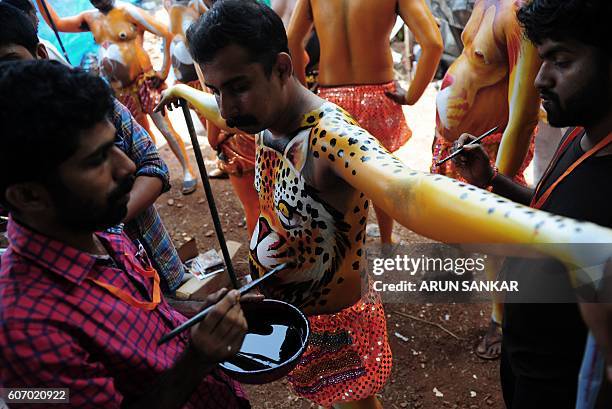 Indian artists paint performers with body-paint depicting tigers as they prepare to take part in the 'Pulikali', or Tiger Dance, in Thrissur on...
