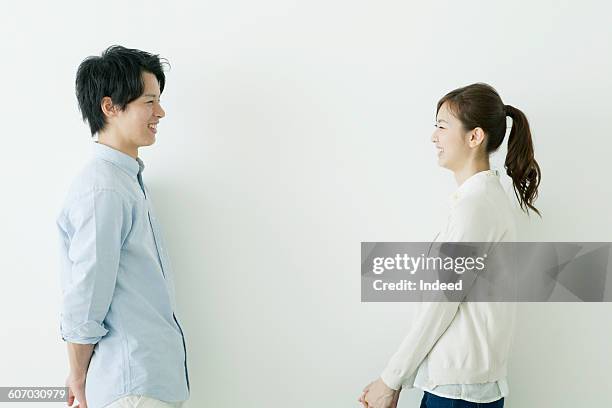 young man and woman smiling face to face - japanischer abstammung stock-fotos und bilder