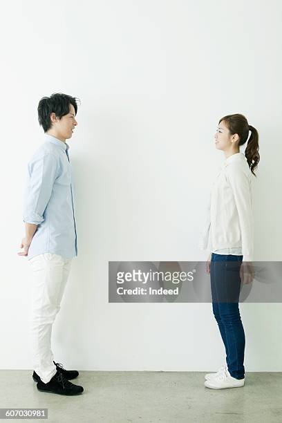 full length of young man and woman smiling face to face - side profile face to face stock-fotos und bilder